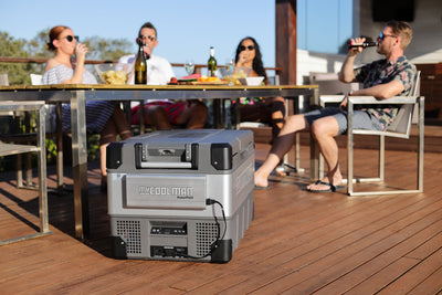 105L: The Fisherman myCOOLMAN with powerpack on deck in front of group of friends sitting at a table